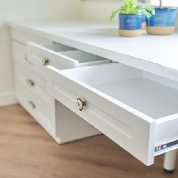 A modern white secretary table with open drawers, featuring a sleek design and soft-close drawer slides for smooth functionality.